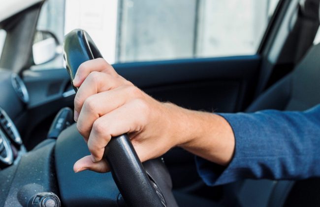 driving-FP Closeup of man holding wheel of car illustrates blog "Should You Get a Lawyer for a DUI?"