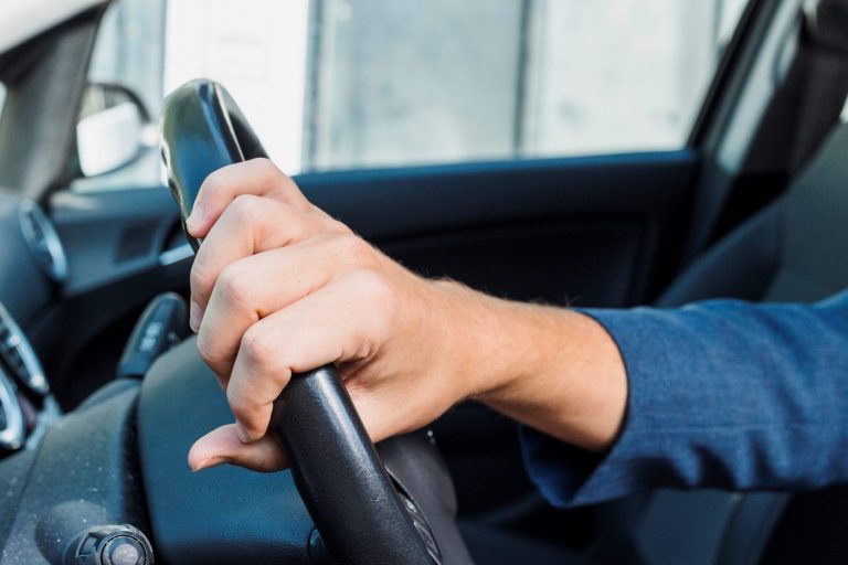 driving-FP Closeup of man holding wheel of car illustrates blog "Should You Get a Lawyer for a DUI?"