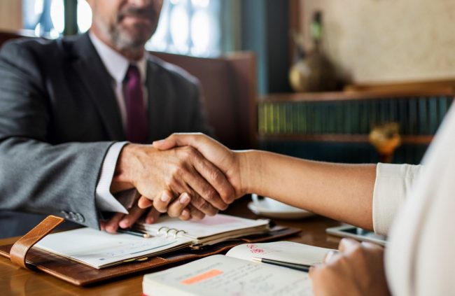 Closeup of lawyer shaking hands with client illustrates blog "What Does It Mean To Have a Lawyer on Retainer?"