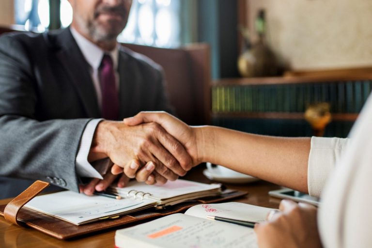 Closeup of lawyer shaking hands with client illustrates blog "What Does It Mean To Have a Lawyer on Retainer?"