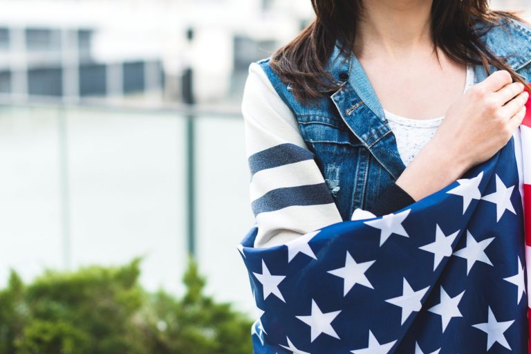 asylum-FP Woman with American flag draped across her shoulders illustrates blog "How Does Asylum Work in the United States?"