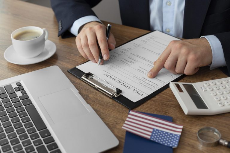 immigration-law-fp Man sitting at desk with laptop and American flag in front of him illustrates blog "What Is Immigration Law?"